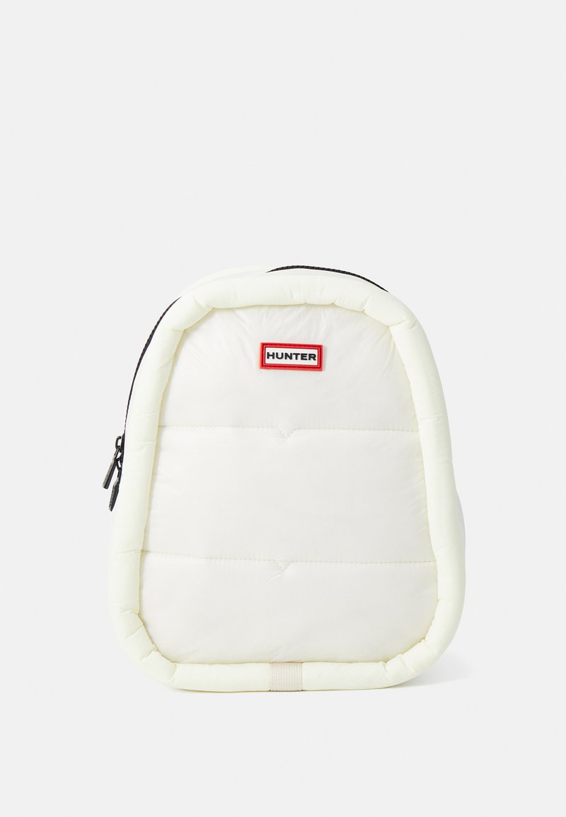 Mochila blanca acolchada con forma redondeada, cremallera negra, logo "HUNTER" en rojo y negro, y sutil textura acolchada.