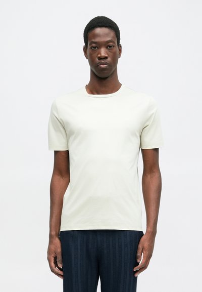 Lühikeste varrukatega hele roheline T-särk, mis on valmistatud pehmest puuvillast, ümarate kaelustega ja tavalise lõikega, kantud tumedate vertikaalsete triipudega pükstega.