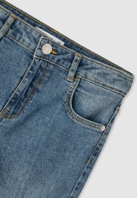 Niebieskie dżinsy o klasycznym kroju, z zapięciem na guzik, kieszeniami z przodu oraz żółtymi akcentami w stichingu. Miękka tekstura z delikatnymi przetarciami.