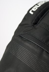 Mustat pehmeät hanskat, joissa on teksturoidusta kankaasta valmistettu pinta, vaakasuorat raidat ja sileä nahkapaikka. Logo painettuna valkoisena yläreunaan.