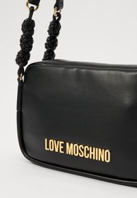 Black leather crossbody bag with a gold "LOVE MOSCHINO" logo and a braided handle. Smooth texture with polished hardware accents.