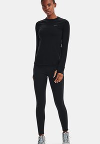 Zwarte lange mouwen sportshirt en aansluitende leggings, gemaakt van lichtgewicht stof, met een soepele textuur en subtiele logo-detail.