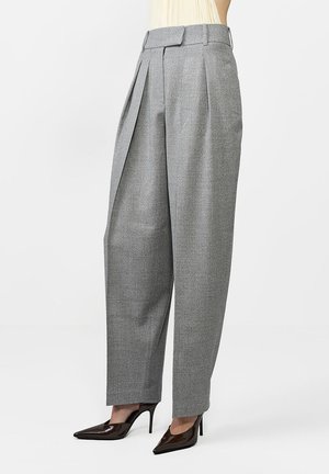 Szare spodnie w kant z fakturowanej tkaniny, z zwężającymi się nogawkami i szerokim pasem. W zestawieniu z błyszczącymi, czółenkami o spiczastych noskach i wysokim obcasie.