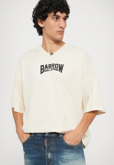 Cream short-sleeve T-shirt with a black "BARROW HALL OF FAME" graphic. Features a V-neck and a yellow accent near the collar.