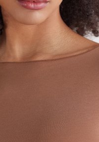 Brązowy, elastyczny top o gładkiej fakturze i okrągłym dekolcie, z delikatnymi przeszyciami wzdłuż brzegów.