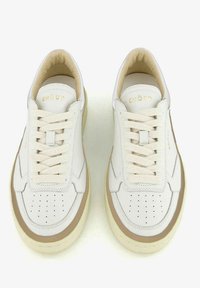 Sneakers in pelle bianca con lacci e interno color crema. Presentano perforazioni sulla punta, accenti beige sui lati e una suola spessa.