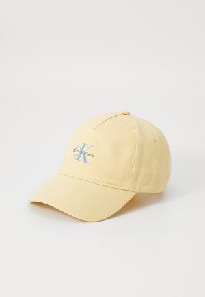 Hellgelbe Baseballkappe mit gebogenem Schirm, mit hellblauem "CK Calvin Klein" Logo auf dem Frontpanel, auf weißem Hintergrund.