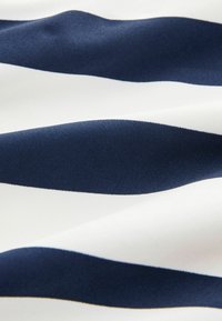 Navyblauw en wit gestreepte stof met een gladde textuur. De strepen wisselen van breedte, waardoor een gedurfde, contrasterende patroon ontstaat.