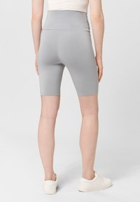 Grijze hoge fietsbroek van soepel, rekbaar materiaal, eindigend net boven de knieën, met een naadloos ontwerp en zonder zichtbare zakken.
