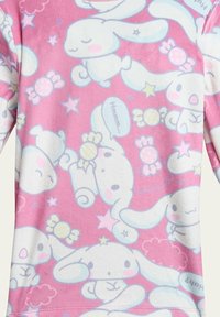 Pink fabric featuring a repeated pattern of pastel bunnies, candies, and stars. The design includes light blue and white accents.