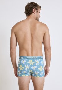 Blå blommönstrade boxershorts med Jockey-midjeresår. Har gula och lavendelfärgade blommor på ett glatt tyg, åtsittande design.