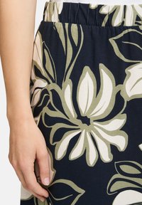 Blumenmusterrock mit dunkelblauem Hintergrund, ausgestattet mit großen, cremefarbenen und olivgrünen Blumen. Elastischer Bund mit glatter Textur.