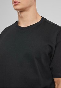 Svart coton t-skjorte med rund hals, korte ermer og en jevn, glatt tekstur med subtile sømdetaljer på skuldrene.