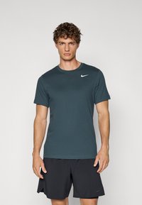 Nike lyhythihainen t-paita tumman teal-värissä, valmistettu hengitt�ävästä kankaasta. Ominaisuuksiin kuuluu pyöreä kaula-aukko ja pieni valkoinen logo vasemmassa rintakohdassa.