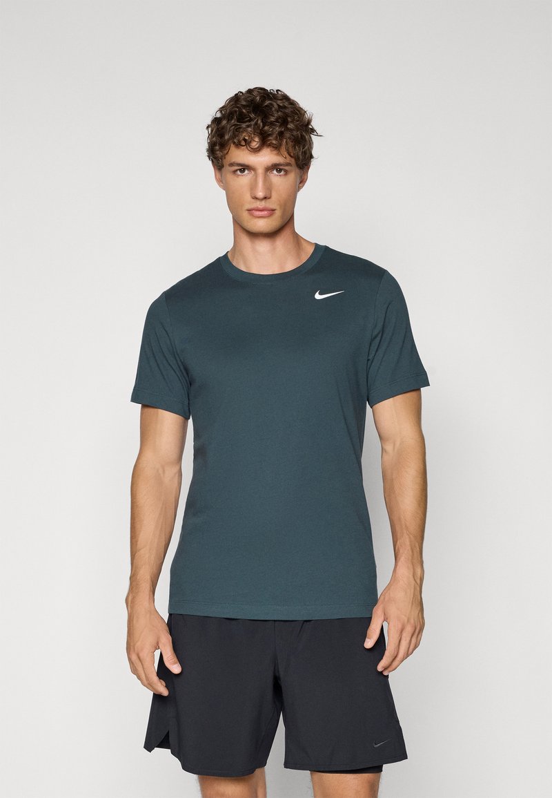 Nike lyhythihainen t-paita tumman teal-värissä, valmistettu hengittävästä kankaasta. Ominaisuuksiin kuuluu pyöreä kaula-aukko ja pieni valkoinen logo vasemmassa rintakohdassa.