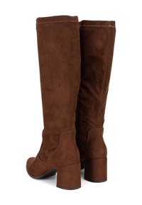 Par de botas altas de mujer de ante marrón con tacones gruesos, mostradas desde ángulos trasero y lateral sobre fondo blanco.