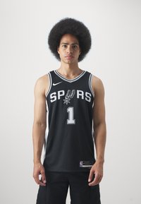 Juodas krepšinio marškinėlis su baltais užrašais "SPURS" ir "#1". Su Nike logotipu ir šonų akcentais. Tinklinė tekstūra.