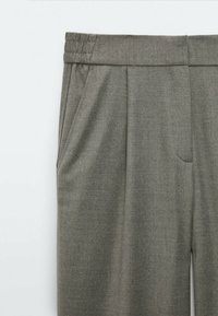 Pantalon à taille élastique grise avec poches latérales et plis avant, fabriqué en tissu doux et texturé.