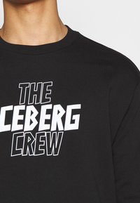 Felpa nera con collo a girocollo caratterizzata da grandi scritte bianche che dicono "THE ICEBERG CREW". Tessuto morbido con una vestibilità rilassata.