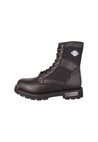 Bota de cuero negro con cordones y suela de goma, puntera reforzada, detalles en panel de nailon y acento de logo metálico. La altura llega a la mitad de la pantorrilla.