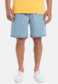 Lichte blauwe denim shorts met een relaxte pasvorm, een rafelige zoom en zijzakken, gecombineerd met witte vetersneakers.