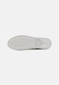 White rubber shoe sole featuring a textured surface, circular logo, and subtle ridges for grip and style. No visible patterns or accents.