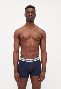 Navy modri bombažni bokser gaćice z belim pasom, na katerem so zelene in modre črte ter logotip "Levi's". Preprost in prilegajoč dizajn.