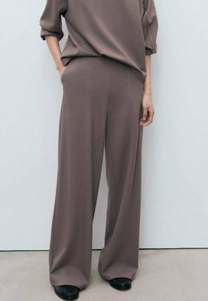 Loose-fitting brown fabric trousers with a high waist, wide legs, and side pockets, paired with a matching oversized top.