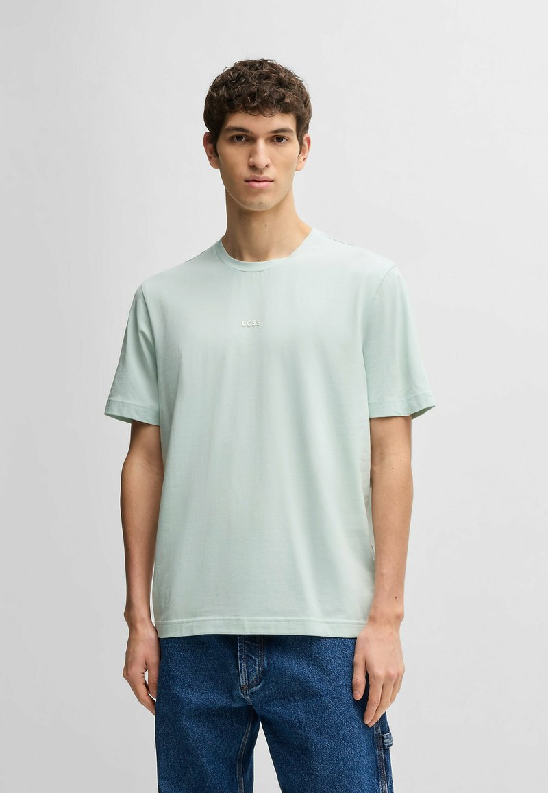 Light green cotton t-shirt with a crew neck, short sleeves, and a subtle "BOSS" logo centered on the chest. Worn with dark denim pants.