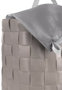 Rechteckiger, geflochtener Korb in einem hellgrauen Farbton mit strukturierter Oberfläche; ausgestattet mit einem wasserdichten grauen Stoffdeckel mit Tropfen.