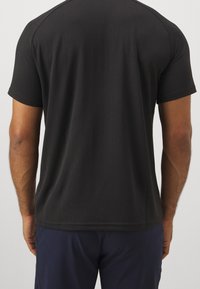 Czarna koszulka z pionowym prążkowanym wzorem, krótki rękaw, okrągły dekolt oraz dopasowany krój. Materiał wydaje się gładki i elastyczny.