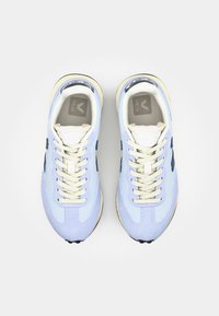 Baskets en maille bleu clair et daim, avec des lacets crème, une semelle beige et des accents bleu marine. La languette porte un logo.