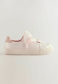 Sneaker en satin rose clair avec un bout arrondi, un détail en ruban sur le côté et une semelle en caoutchouc texturé de couleur blanche. Fini doux et brillant avec des accents beiges.