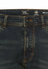 Granatowe dżinsy o wysokiej elastyczności, z kontrastowymi przeszyciami, metalowym zapięciem na guzik oraz metką Camel Active na pasku.