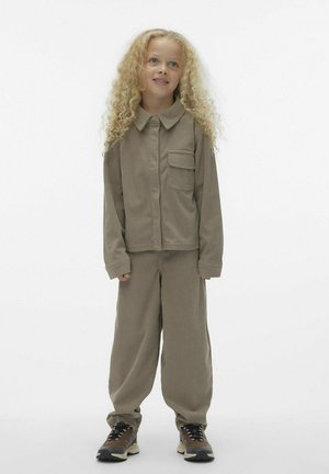 Brun ribbad outfit bestående av en skjorta med krage och knappar samt en ficka, tillsammans med matchande lösa byxor och mörka sneakers.