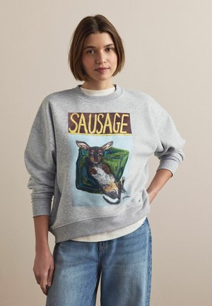 Szara bluza z kolorowym obrazkiem psa wypoczywającego na zielonej sofie, z napisem "SAUSAGE" nad obrazkiem. Miękka tkanina, luźny krój.