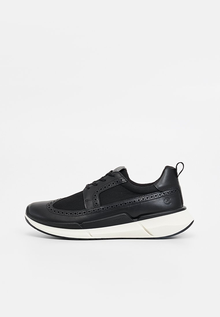 Baskets noires composées d'un mélange de matériaux en cuir et en mesh, à bout rond, avec des détails perforés et une semelle blanche rembourrée.