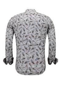 Langarmshirt van licht stof met een veerpatroon in tinten blauw en bruin op een crèmekleurige achtergrond. Klassieke kraag en manchetten met knopen.