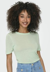 Top corto verde chiaro a maniche corte con scollo rotondo, realizzato in un materiale morbido, caratterizzato da una texture liscia e un design aderente.