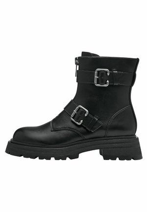 Bottines en cuir noir avec des sangles à double boucle, une fermeture éclair latérale et une semelle en caoutchouc épaisse. Elles présentent un bout arrondi et une finition texturée.