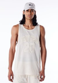 Beige mesh singlet med "NEW ERA" og "20" preget i større tekst. Kombinert med en lysegrå caps med en sort og hvit logo.