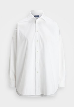 Biała koszula z długim rękawem zapinana na guziki, klasyczny kołnierz, widoczne guziki z przodu oraz metka Polo by Ralph Lauren wewnątrz kołnierza.