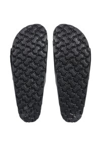Black rubber shoe soles with a textured, geometric tread pattern for grip and traction. Features rounded edges and a sturdy design.
