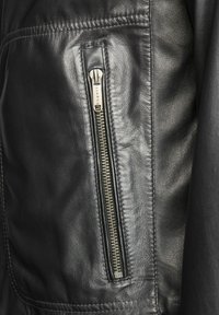 Zwarte leren jas met een ritszak, voorzien van metalen hardware en gestikt detail, met een gladde textuur.