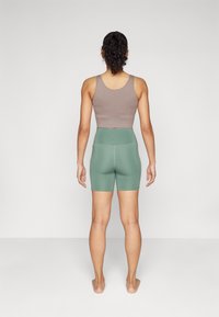 Top court en maille gris associé à un short de vélo taille haute vert menthe, présentant une texture lisse et un design ajusté.