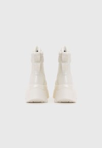 Sneakers albe înalte, dintr-un finisaj neted din piele, cu vârful rotunjit, guler căptușit și talpă groasă, robustă. Cusăturile detaliate sunt vizibile.