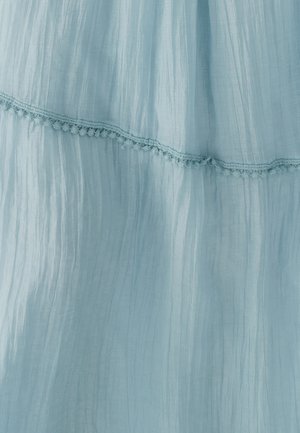 Vestido azul claro hecho de tela arrugada, con un borde de encaje decorativo a lo largo del dobladillo. La textura es suave y ligera.