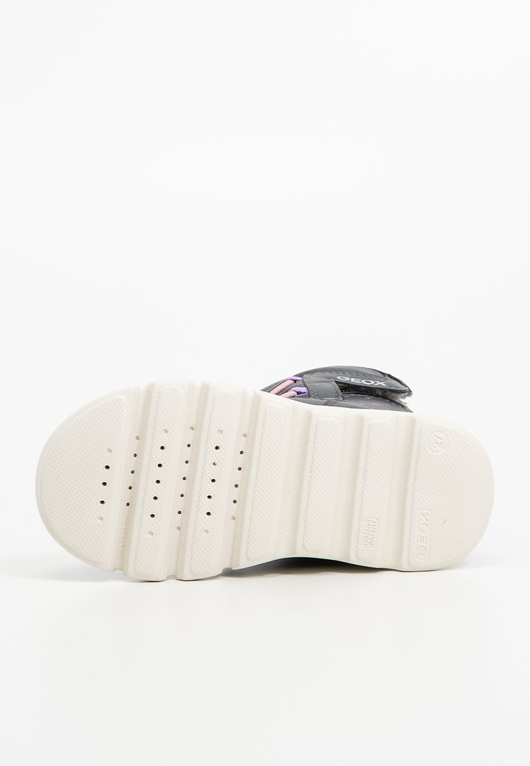 Schwarzer Sneaker mit pinken und lila Riemen, strukturiertes schwarzes Obermaterial, weiße Gummisohle und mehrere Entwässerungsöffnungen an der Unterseite.