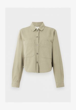 Veste beige raccourcie à manches longues, col, boutons sur le devant et deux grandes poches poitrine sur un fond uni.