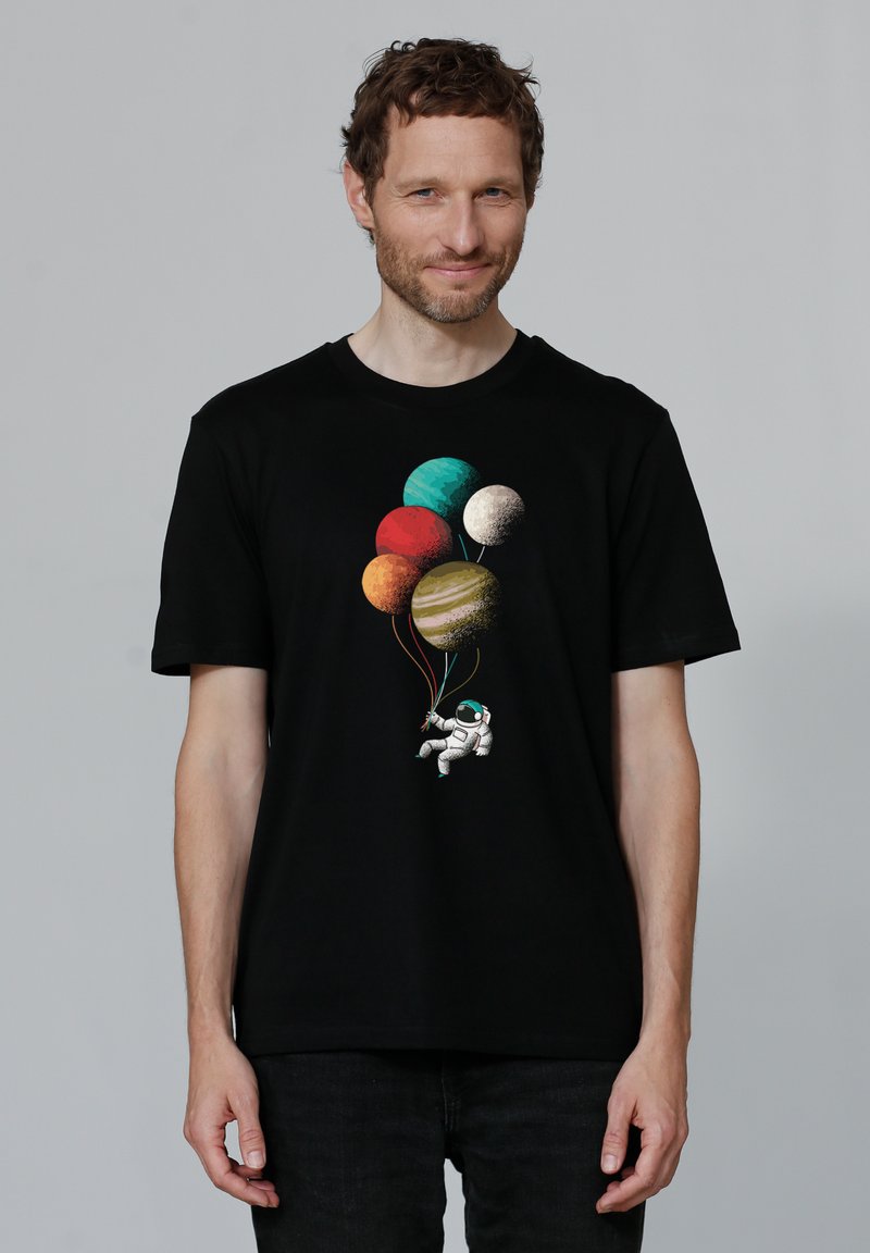 T-shirt en coton noir avec un graphique coloré de planètes et un astronaute tenant des cordes de ballons. Manches courtes et coupe standard.